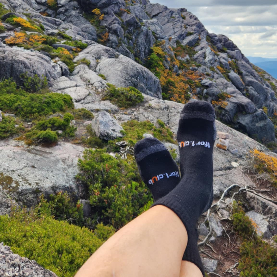 Person wearing socks with visible branding on a mountain landscape